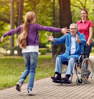 support worker pushing elderly man in wheelchair on walk to meet grandchild